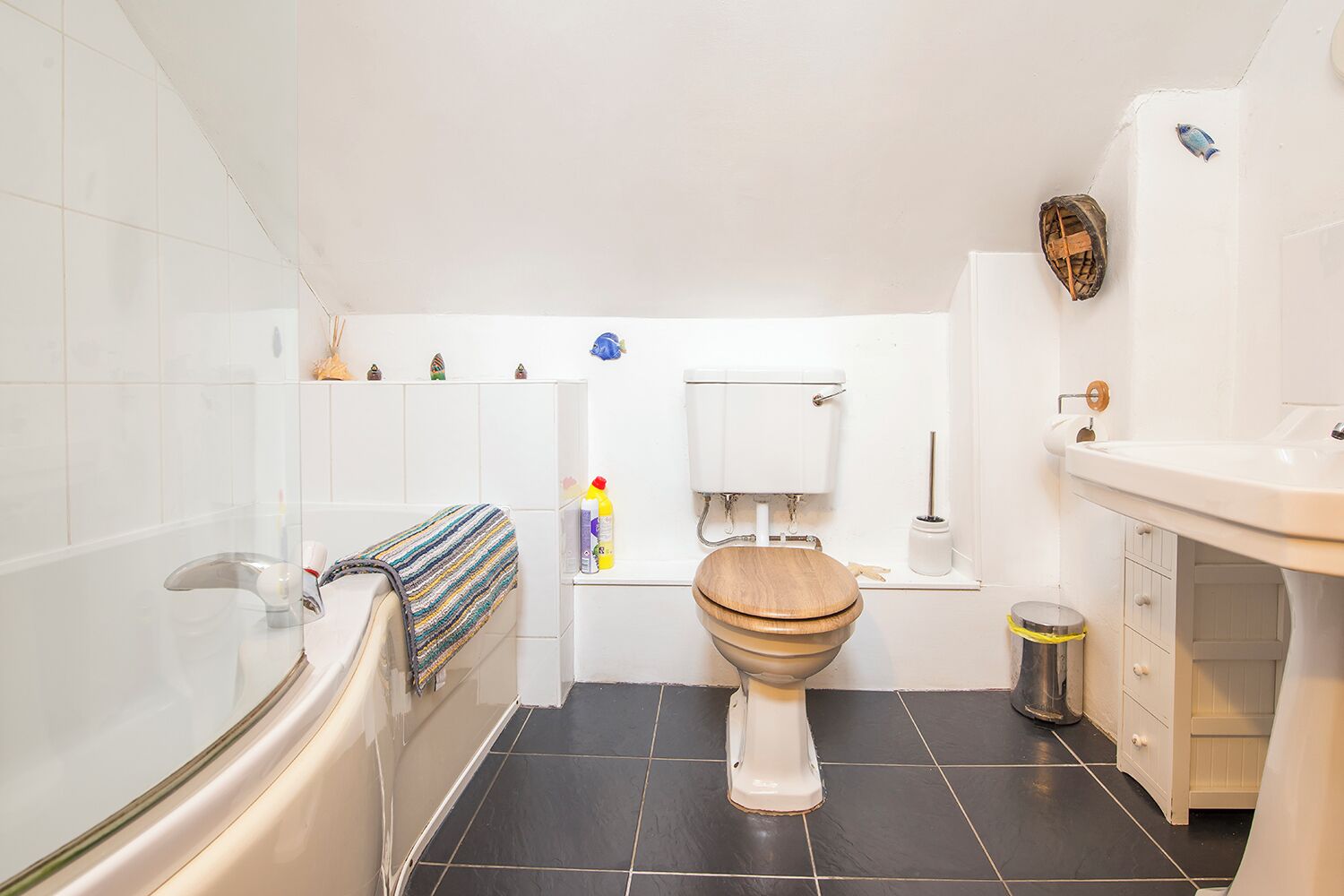 Een badkamer met bad, toilet, wastafel en betegelde vloer.