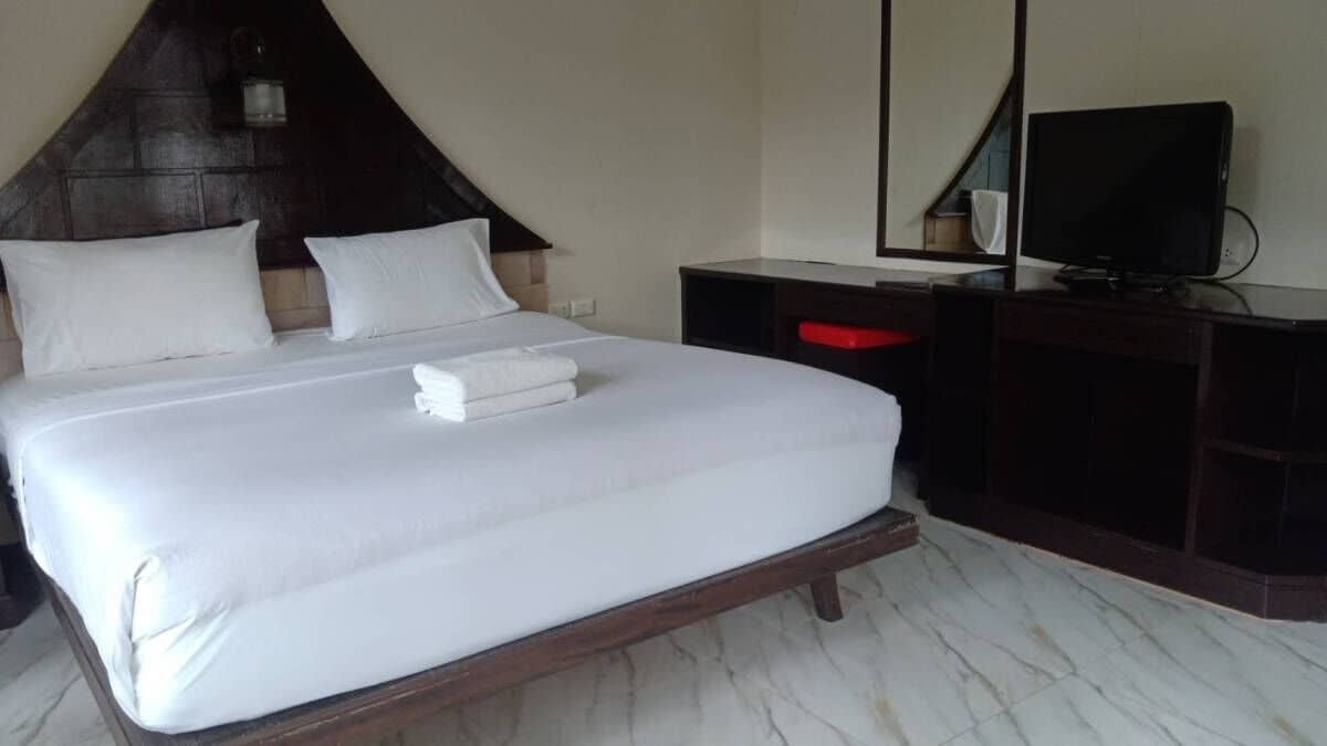 A hotel room with a large bed, a TV, a desk, and a mirror.