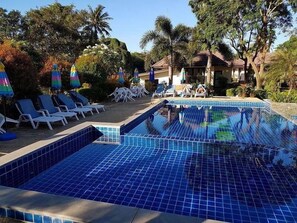 A swimming pool with blue tiles, surrounded by lounge chairs and umbrellas. - Iyara Boty Resort (Ko Chang)