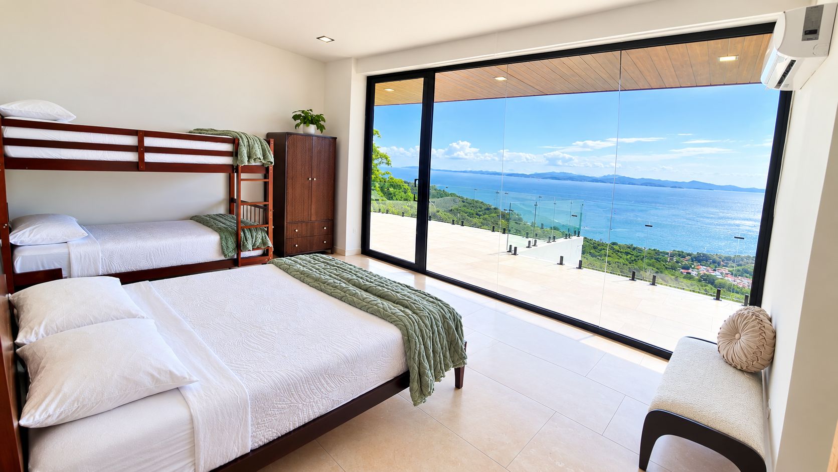 A bedroom with a large window, a bunk bed, a bedside cabinet, and a view of the sea.