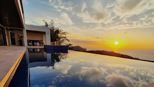 Una piscina infinita moderna con vistas despejadas al atardecer sobre el océano.