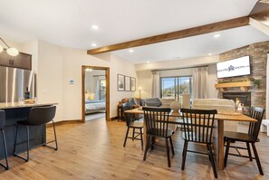 Una sala de estar moderna con chimenea, un comedor con muebles de madera y una cocina con refrigerador de acero inoxidable.