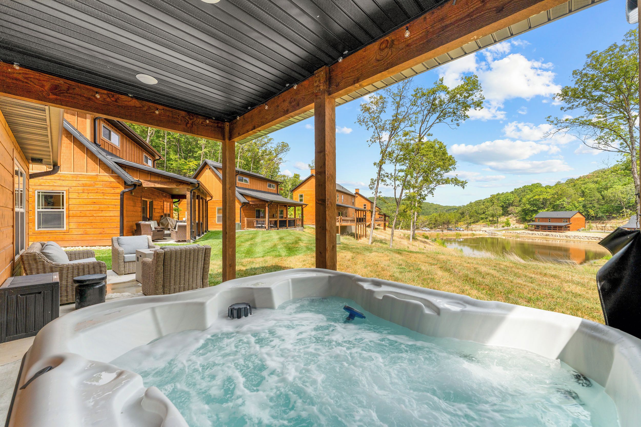 A hot tub with a view of a wooden cabin and a lake.