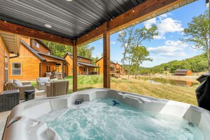 Un jacuzzi con vistas a una cabaña de madera y un lago.