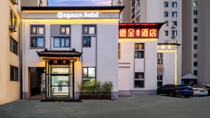 Un hotel con entrada de arquitectura tradicional china, un letrero de neón y un área de estacionamiento.