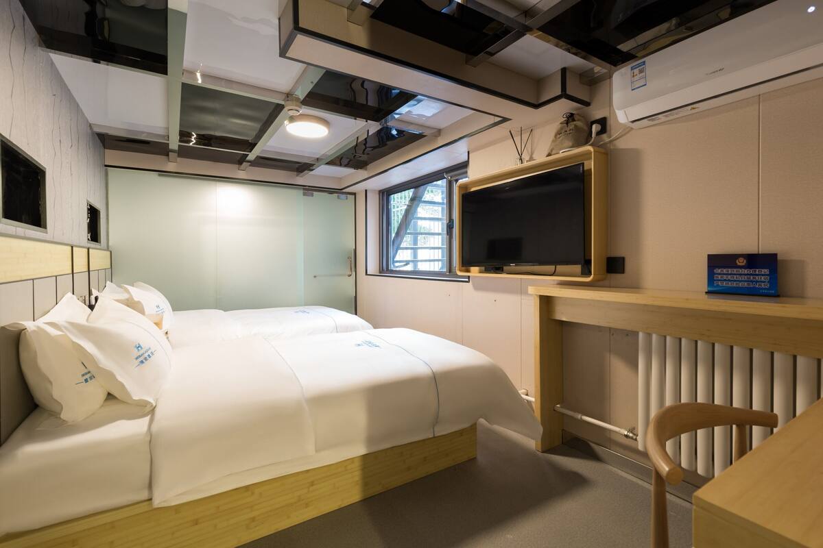 A modern hotel room with a bed, a desk, and a television.