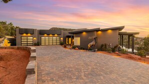 A modern house with a paved driveway, garage doors, and a deer statue. - Zendona | Luxury Estate | Hot Tub, Putting Green and Fire Pits | Stunning Views | Near Trails (Sedona)