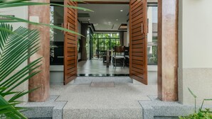 A modern entrance with open wooden doors leading to a dining area with tables and chairs. - Rose Pool Villa, The perfect private oasis (Rawai)