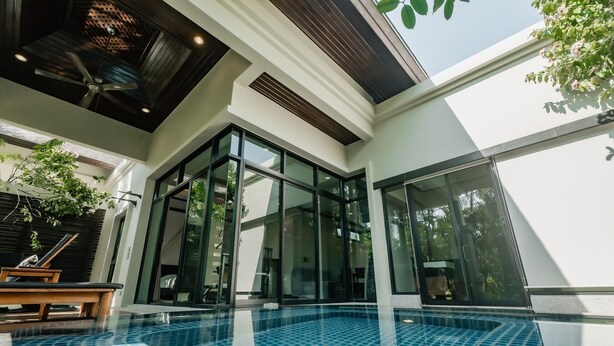A modern indoor swimming pool with glass walls, a ceiling fan, and a wooden bench. - Rose Pool Villa, The perfect private oasis (Rawai)