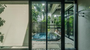 A view through a window of a swimming pool area with a tiled deck, surrounded by greenery. - Rose Pool Villa, The perfect private oasis (Rawai)