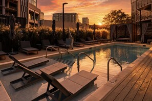 A rooftop pool with sun loungers and a view of the city skyline at sunset. - Rhythm & Rooftop Penthouse | Walk to Broadway | Skyline Views | Pool & Gym (Nashville)