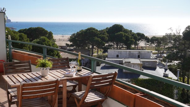 A balcony with a wooden table and chairs, overlooking a beach and ocean. - Medas Park 261 - L'Estartit, Center (Estartit (L´))
