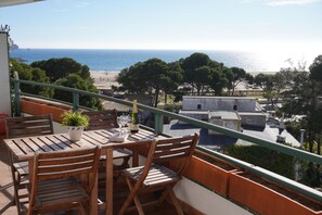A balcony with a wooden table and chairs, overlooking a beach and ocean. - Medas Park 261 - L'Estartit, Center (Estartit (L´))