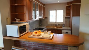 A kitchen with wooden cabinets, a microwave, a sink, and a window. - Medas Park 261 - L'Estartit, Center (Estartit (L´))