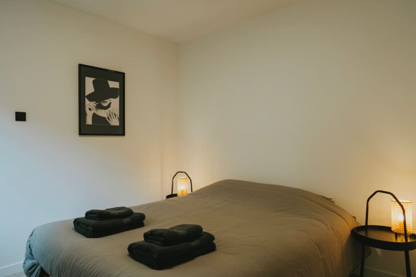 A bedroom with a large bed, two bedside lamps, and a framed picture on the wall.