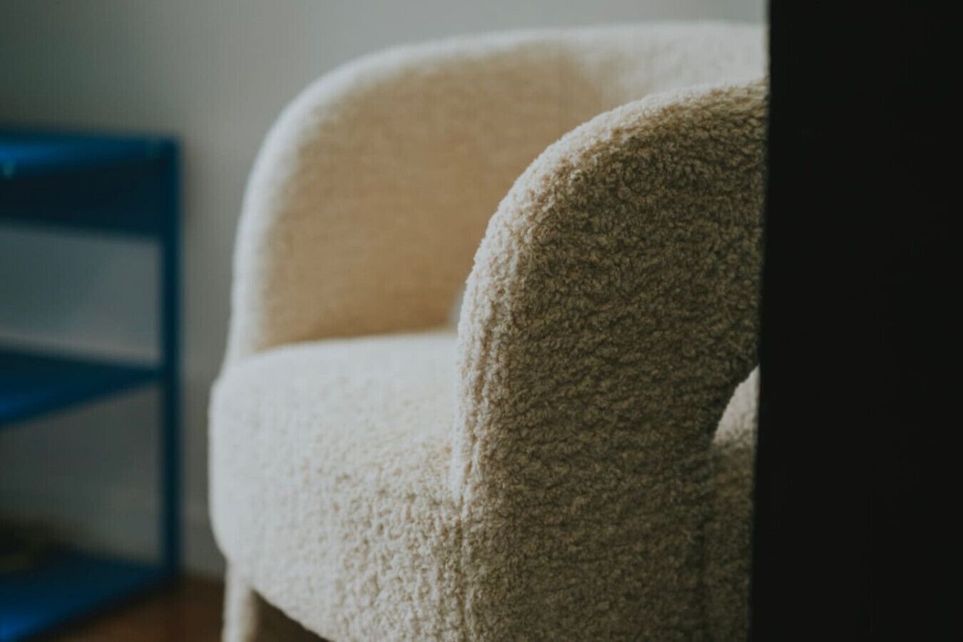 Un gros plan d’un fauteuil à la texture marquée, de couleur claire, dont on aperçoit la structure en bois.