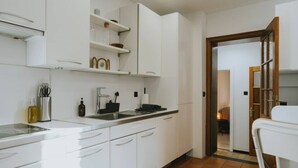 A modern kitchen with white cabinets, a stainless steel sink, and a countertop with kitchen utensils. - 2 bedroom apartment in Liege (Saint Leonard) (Liège)