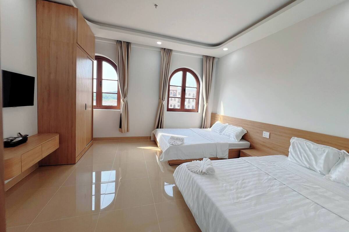 A hotel room with two beds, a TV, and a wooden wardrobe.