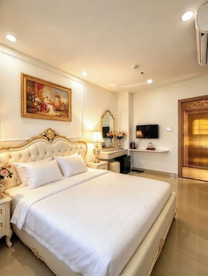 Une chambre d’hôtel avec un grand lit, un tableau au mur, une télévision et un mini-bar.