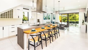 A modern kitchen with a central island, pendant lights, and a large window overlooking a garden. - Lotus Villas #1-Leeward Palms. Your Gateway to Paradise & Step into Serenity.... (Leeward Settlement)