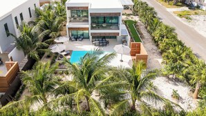 A modern two-story house with a pool, surrounded by palm trees and a well-maintained lawn. - Lotus Villas #1-Leeward Palms. Your Gateway to Paradise & Step into Serenity.... (Leeward Settlement)