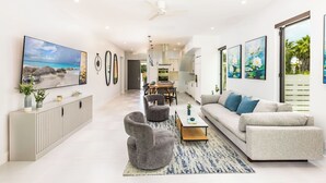 A modern living room with a sofa, armchairs, a coffee table, and artwork on the walls. - Lotus Villas #1-Leeward Palms. Your Gateway to Paradise & Step into Serenity.... (Leeward Settlement)