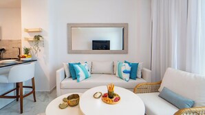 A modern living room with a white sofa, a dining area with a bar, and a kitchen visible in the background.