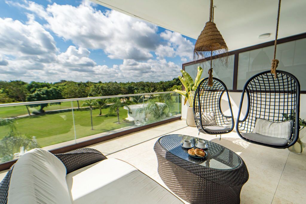 Een balkon met rieten meubilair, een hangstoel en een tafel met een dienblad eten.