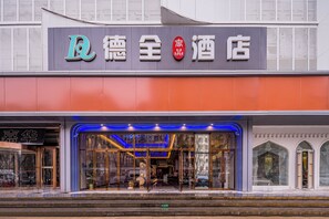 Un hôtel doté d’une façade moderne, d’une grande entrée en verre et d’une enseigne bien visible avec des caractères chinois.
