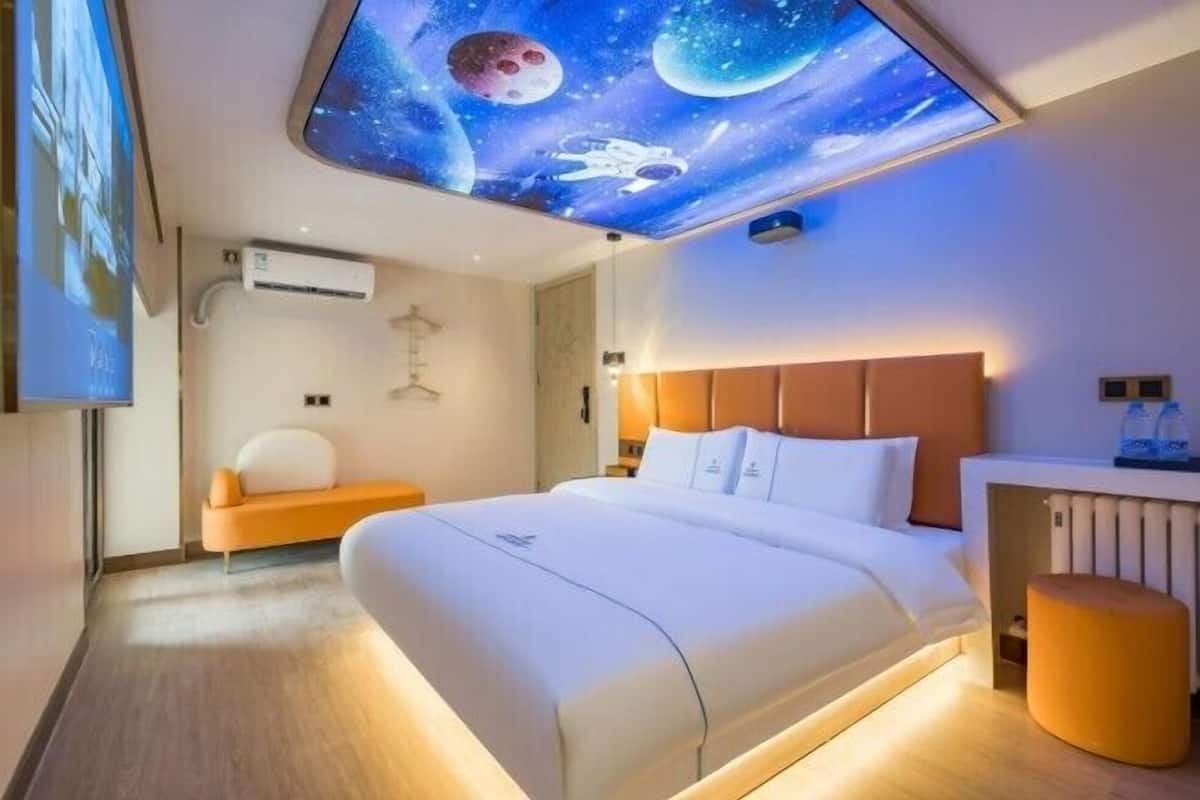 Een hotelkamer met een bed, zithoek en een plafondschildering van de ruimte.