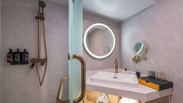 A bathroom with a shower, a sink, a mirror, and toiletries.