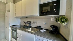 Une cuisine moderne équipée d’un four, d’un micro-ondes et d’un lave-vaisselle intégrés.