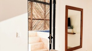 Un interior moderno con una escalera que lleva a un balcón, un sofá y un espejo en la pared.