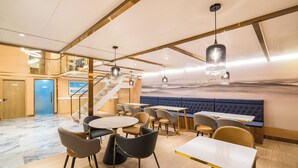 A modern restaurant interior with a staircase, seating areas, and a blue cushioned bench. - Dequan Luxury WangJing Hotel (Beijing)