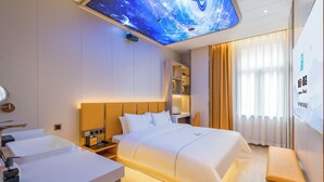 A modern hotel room with a large bed, a bedside table, a built-in shelf, a ceiling projector displaying a starry sky, and a large window with curtains. - Dequan Luxury WangJing Hotel (Beijing)