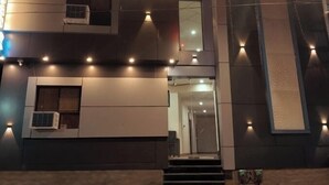 A modern building with multiple floors, large windows, and a staircase leading to the entrance. - Hotel Abhinandan (Ayodhya)