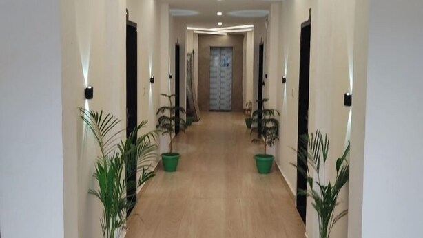 A modern hallway with wooden flooring, potted plants, and recessed lighting. - Hotel Abhinandan (Ayodhya)