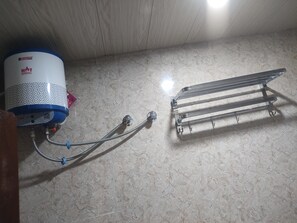 A water heater, a metal rack, and a textured wall. - Hotel Abhinandan (Ayodhya)