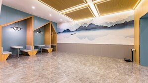 A modern waiting area with a marble floor, wooden seating, and a mural of mountains. - Anhui Culture Hotel (Beijing)