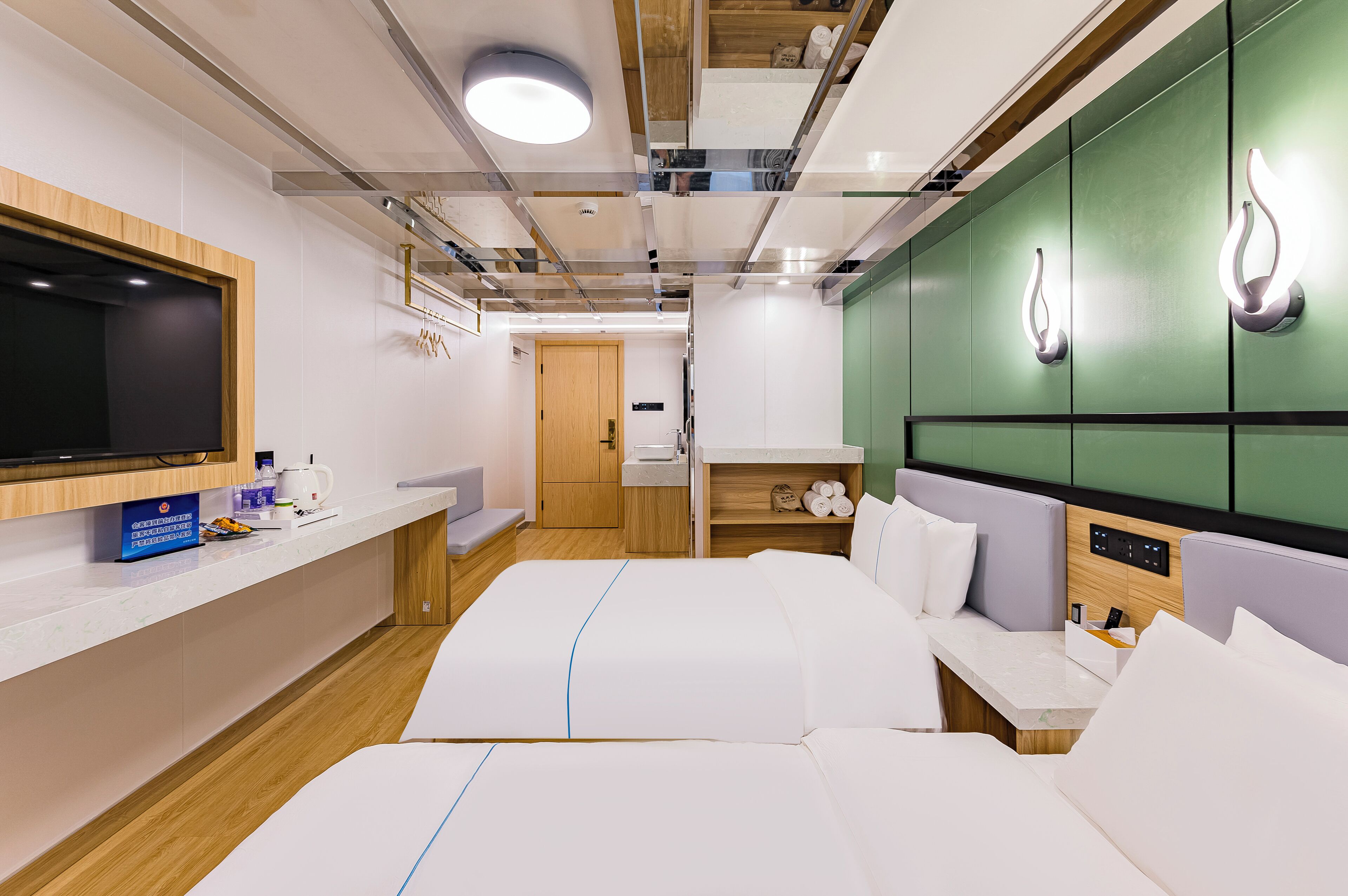 Ein modernes Hotelzimmer mit einem großen Bett, einem Fernseher, einem Holzschrank und einer grünen Akzentwand.