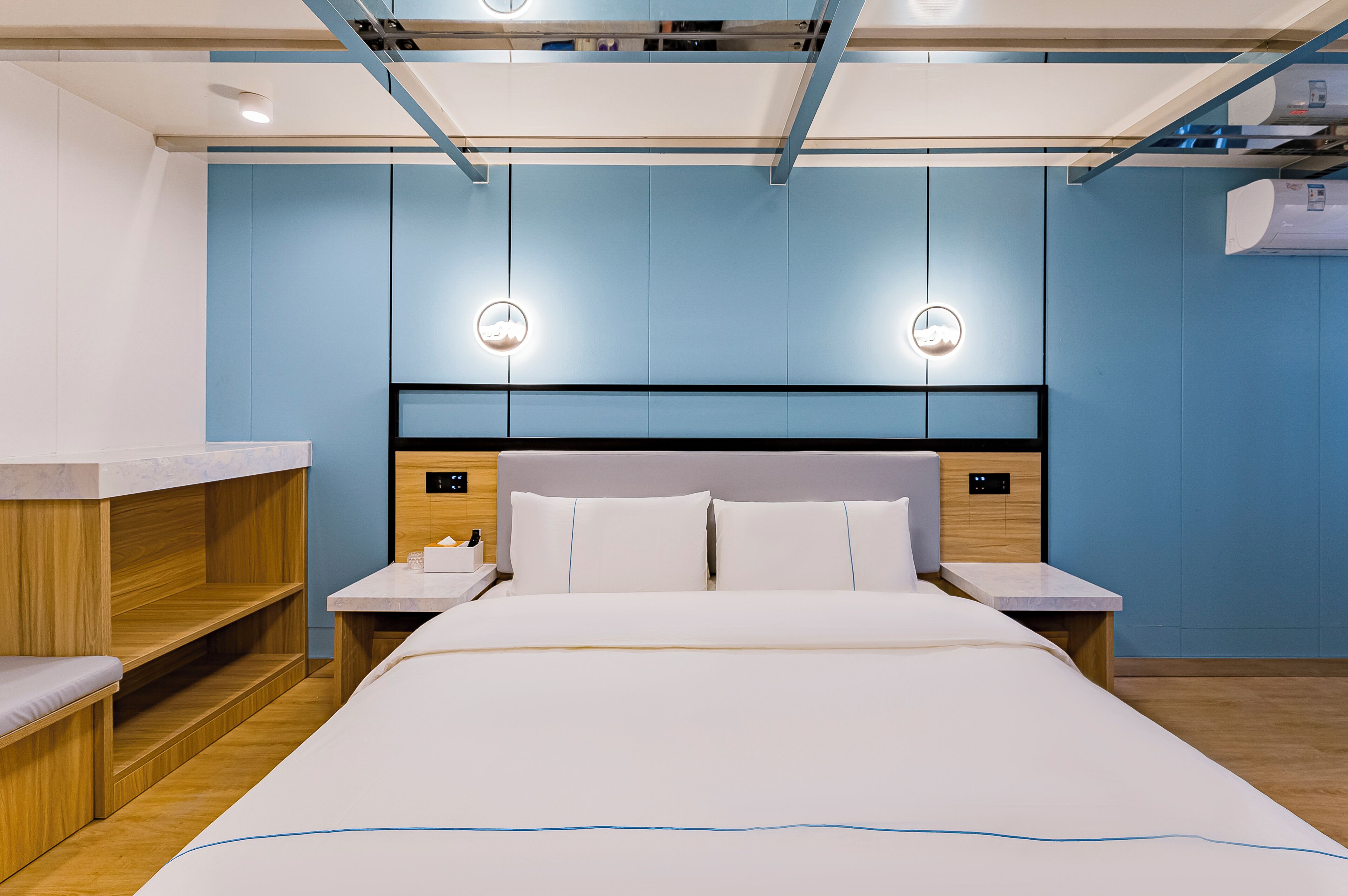 Une chambre d’hôtel moderne avec un grand lit, des tables de chevet en bois et une banquette intégrée.