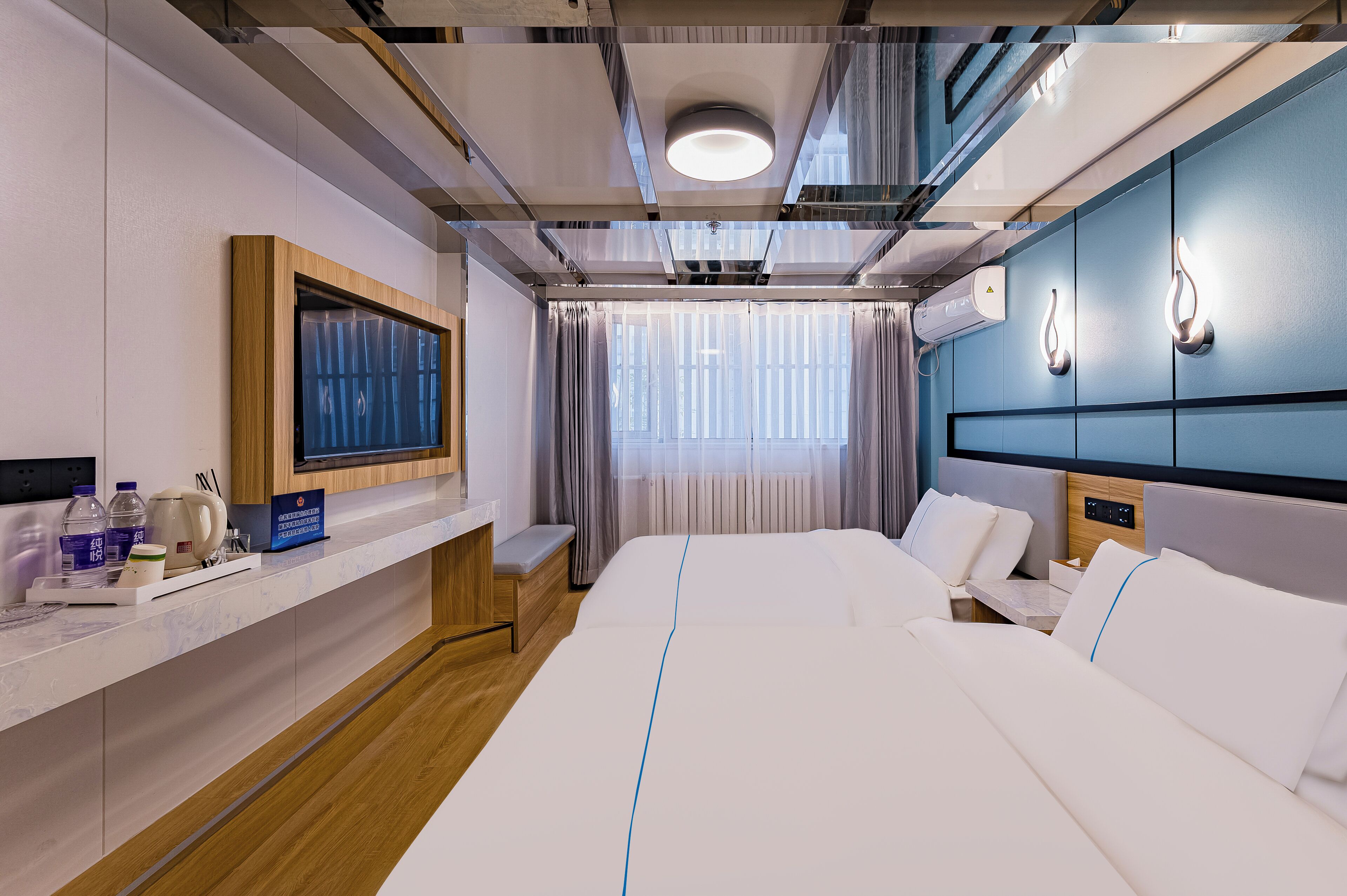 Habitación de hotel con una cama grande, un escritorio con computadora, televisión y ventana con cortinas.