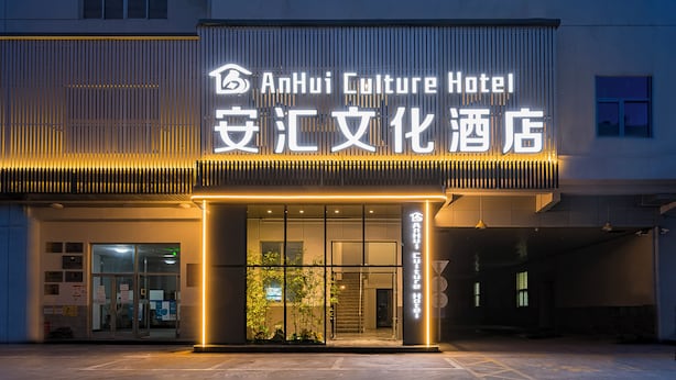 The exterior of AnHui Culture Hotel with a modern facade, large glass entrance, and illuminated signage. - Anhui Culture Hotel (Beijing)