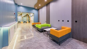 A modern lobby with seating areas, a reception desk, and a wall-mounted coat rack. - Anhui Culture Hotel (Beijing)