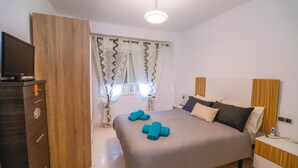 A bedroom with a bed, a wooden wardrobe, a nightstand, and a television. - Fuente de Piedra Apartment (Torre Del Mar)