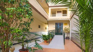 A multi-level building with a central staircase, potted plants, and a tiled floor. - Fuente de Piedra Apartment (Torre Del Mar)