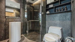 Ein modernes Badezimmer mit einer gläsernen Duschkabine, einem freistehenden Waschbecken und einer Toilette mit Handtuch.