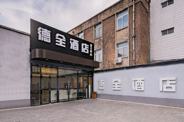 A hotel entrance with a large sign, glass doors, and a paved walkway. - Dequan HoteTempleofHeaven EastGateBranch (Beijing)