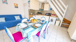 Un espace de vie compact comprenant un coin repas, une kitchenette et un escalier menant à un niveau supérieur.