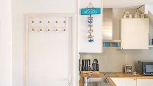 Une cuisine avec des armoires blanches, un plan de travail en bois, un évier et une enseigne suspendue sur laquelle on peut lire « BIENVENUE ».
